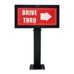 Front view of a black-framed "DRIVE THRU" directional sign with a right-pointing arrow, mounted on a metal post.