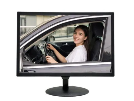 Computer monitor on a stand displaying a live video feed of a smiling woman driving her car, used for drive-thru order-taking.